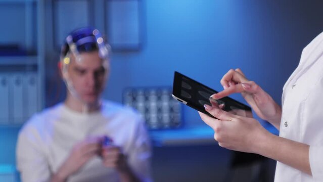 Man wearing EEG topographer for examining brain, doctor making electrogram of scalp activity. Researching of brain work using electroencephalography headset.