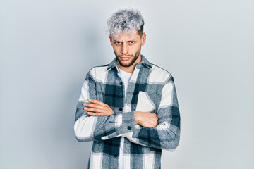 Young hispanic man with modern dyed hair wearing casual shirt skeptic and nervous, disapproving...