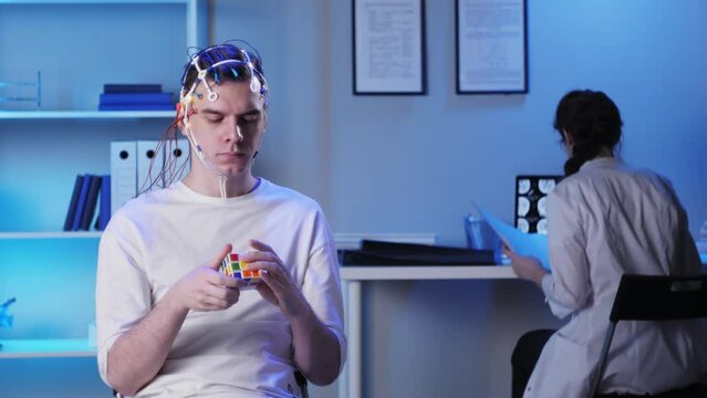 Man wearing EEG topographer for examining brain, doctor making electrogram of scalp activity. Researching of brain work using electroencephalography headset.