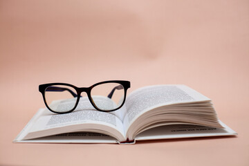book with glasses on a beige background