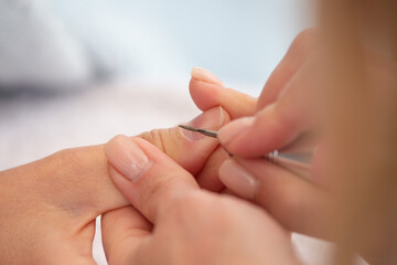 Manicure process in beauty salon, cleaning of nails by a milling cutter. Manicurist filing client's nails at table. Removing the nail plate with a milling machine. nail care concept