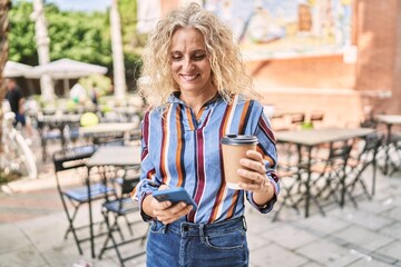 Middle age blonde woman using smartphone drinking coffee at terrace coffee shop