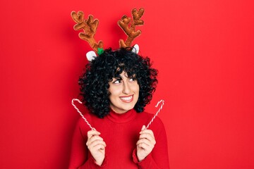Young middle east woman wearing cute christmas reindeer horns smiling looking to the side and...