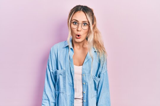 Beautiful young blonde woman wearing casual clothes and glasses afraid and shocked with surprise expression, fear and excited face.
