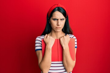 Young hispanic woman holding book skeptic and nervous, frowning upset because of problem. negative person.