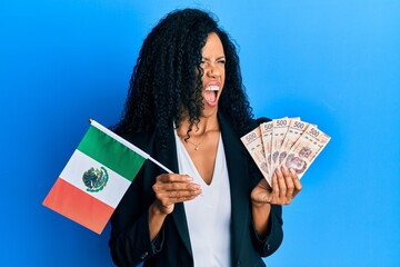 Middle age african american woman holding mexico flag and mexican pesos banknotes angry and mad...