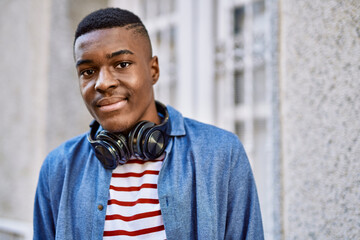 Obraz premium Young african american man smiling happy using headphones at the city.