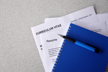 Top view of stack of office documents including resume and cv forms on the desk close to pen and...