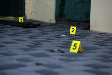 Evidence with yellow CSI marker for evidence numbering on the residental backyard in evening. Crime...
