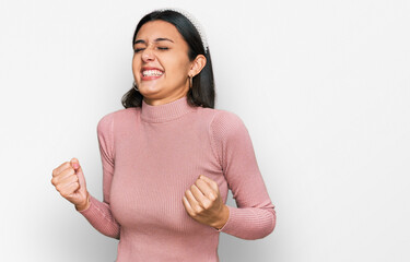 Young hispanic girl wearing casual clothes very happy and excited doing winner gesture with arms raised, smiling and screaming for success. celebration concept.