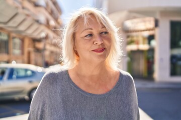 Fototapeta premium Middle age blonde woman with relaxed expression standing at street