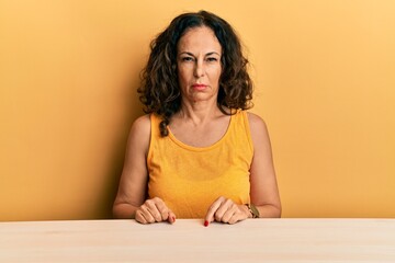 Beautiful middle age woman wearing casual clothes sitting on the table skeptic and nervous, frowning upset because of problem. negative person.