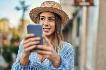 Young hispanic woman smiling happy using smartphone at the city