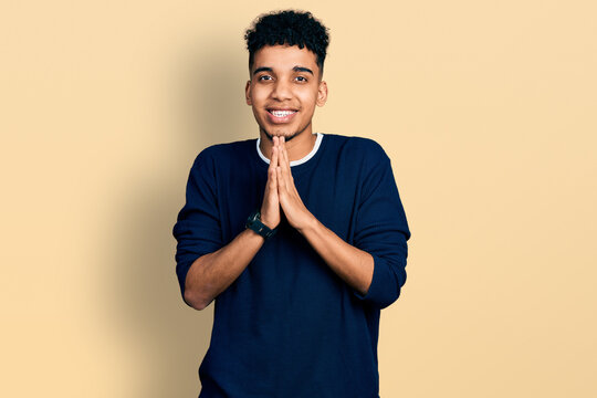 Young african american man wearing casual clothes praying with hands together asking for forgiveness smiling confident.
