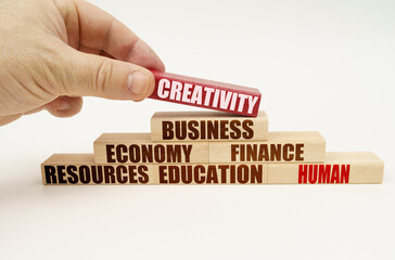 On a white background, the hand adds blocks with inscriptions on a red block, the inscription - CREATIVITY