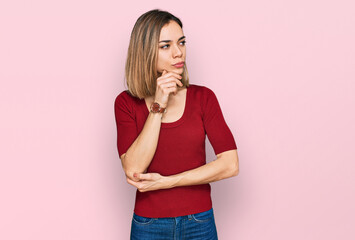 Young blonde girl wearing casual clothes with hand on chin thinking about question, pensive expression. smiling with thoughtful face. doubt concept.