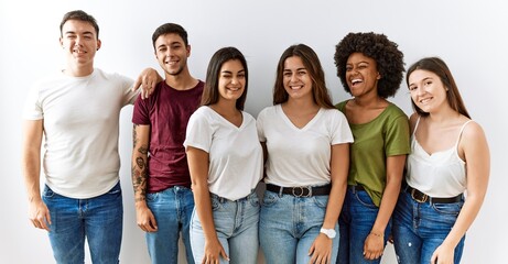Group of young friends standing together over isolated background winking looking at the camera...