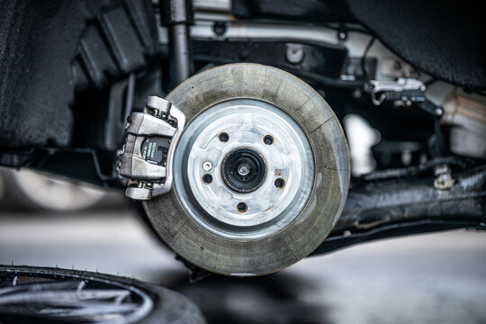 KFZ Mechaniker wechselt die Reifen beim Reifenwechsel und die Bremsscheibe mit den Bremsklötzen am Neuwagen