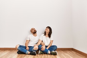 Fototapeta na wymiar Young hispanic couple smiling happy sitting on the floor at empty new home.