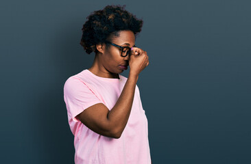 Fototapeta na wymiar African american woman with afro hair wearing casual clothes and glasses tired rubbing nose and eyes feeling fatigue and headache. stress and frustration concept.