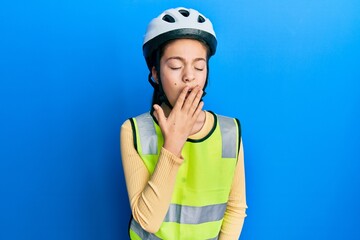 Beautiful brunette little girl wearing bike helmet and reflective vest bored yawning tired covering mouth with hand. restless and sleepiness.