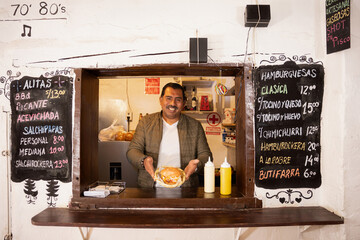 latin man with a mask, serving a sandwich in a south american restaurant