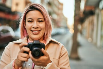 Young hispanic girl smiling happy using reflex camera at the city.