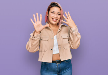 Hispanic woman with pink hair wearing casual clothes showing and pointing up with fingers number nine while smiling confident and happy.