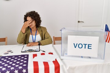 Young hispanic woman at political election sitting by ballot tired rubbing nose and eyes feeling...