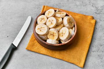 Photo of banana slices in a bowl on a concrete surface