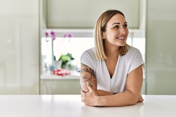 Young caucasian girl smiling happy leaning on the table standing at the kitchen.