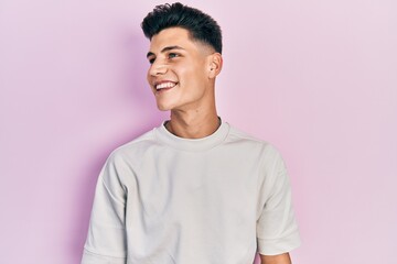 Young hispanic man wearing casual white t shirt looking to side, relax profile pose with natural...