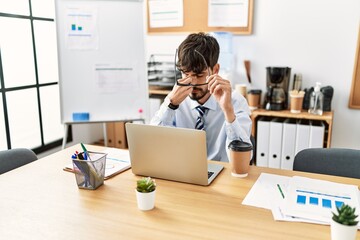 Young hispanic businessman stressed working at the office.