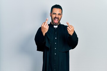 Handsome hispanic man with beard wearing catholic priest robe showing middle finger doing fuck you...