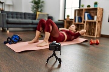 Middle age caucasian sporty woman doing abdominal exercise online lesson at home.