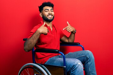 Arab man with beard sitting on wheelchair looking confident with smile on face, pointing oneself...
