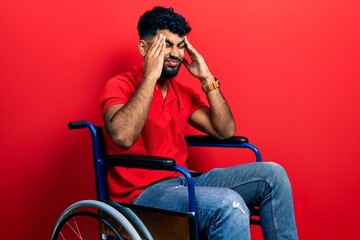 Obraz na płótnie Canvas Arab man with beard sitting on wheelchair with hand on head, headache because stress. suffering migraine.