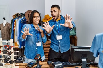 Young interracial people working at retail boutique afraid and terrified with fear expression stop...