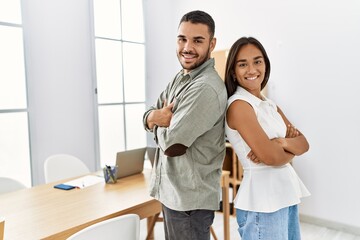 Two latin business workers smiling happy standing with arms crossed gesture at the office.