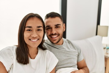 Fototapeta na wymiar Young latin couple smiling happy hugging on the bed at home.