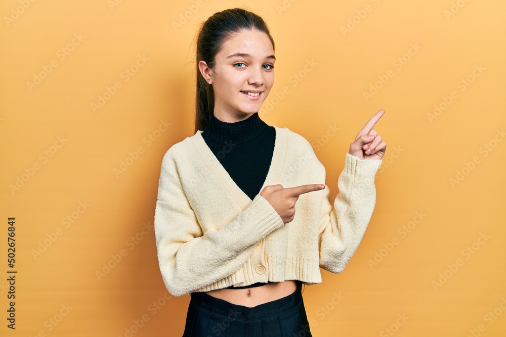 Sticker young brunette girl wearing casual yellow jacket smiling and looking at the camera pointing with two