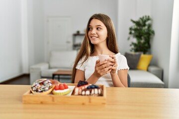 Adorable girl having breakfast sitting on table at home