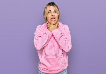 Fototapeta premium Young caucasian woman wearing casual sweatshirt shouting and suffocate because painful strangle. health problem. asphyxiate and suicide concept.