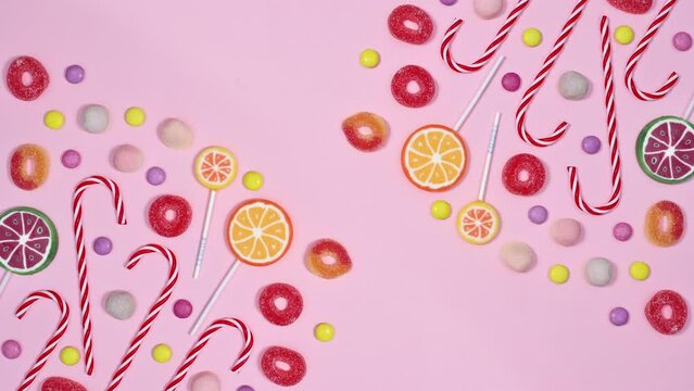Sweet candies and lollipops arrangement move on pastel pink background with copy space. Stop motion flat lay