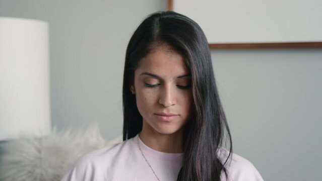Pretty hispanic woman looks down as if praying or feeling defeated in slow motion