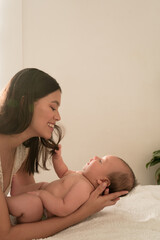 Latin young mother play happy with baby on the bed at home