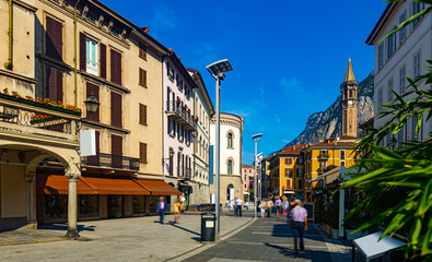 Fototapeta na wymiar View of old town streets of Italian city of Lecco on background of San Martino mountain at sunny day