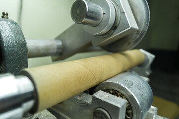 Machine for cutting cardboard bushing for printing house. Cutting cardboard reels and spools for winding paper and film. Equipment for production. Selective focus