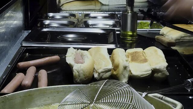 calentando panes de completos o hot dog chilenos para hacer completos italianos en un carro callejero