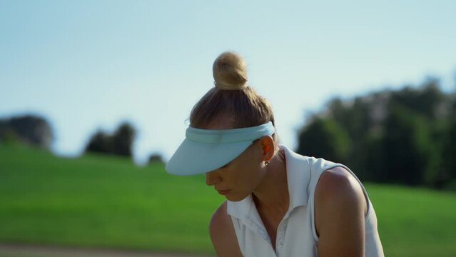 Confident woman playing golf on fairway. Golfer swinging ball at country club.